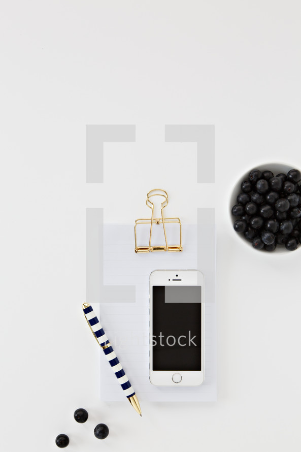 iPhone, clipboard, blueberries, and pen 