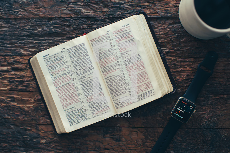 pages of a Bible, smartwatch, and coffee cup 