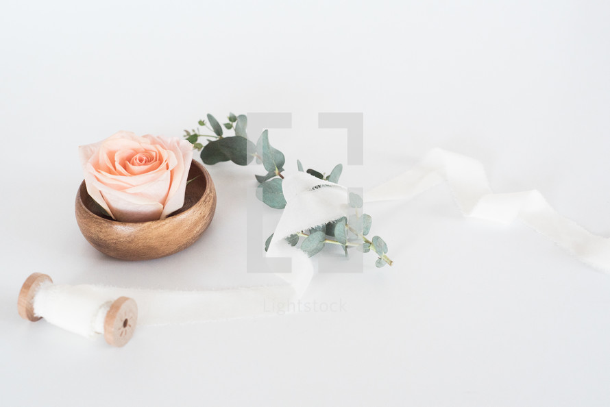 wood bowl, roses, and spool of ribbon 
