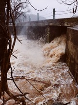water at a dam rushing under a bridge 