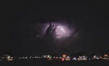 An evening thunderstorm over city lights.