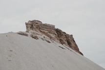 rock formation sticking out of a sand dune 