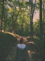 woman walking on a path through a forest 