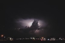Thunderstorm in a night sky over city lights.