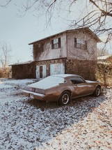 an old car parked in a snowy front yard 