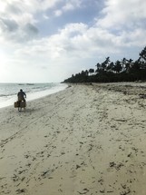 man riding a bicycle on a beach in Zanzibar, Tanzania