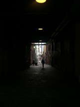 walking through a tunnel into an alley 
