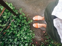 a woman's feet standing in a garden 