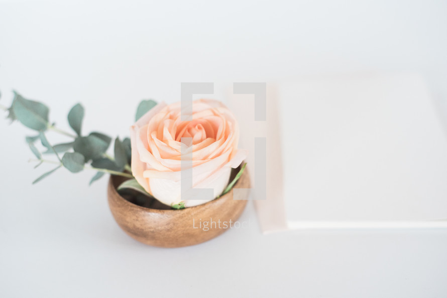 peach rose in a wooden bowl and stationary 