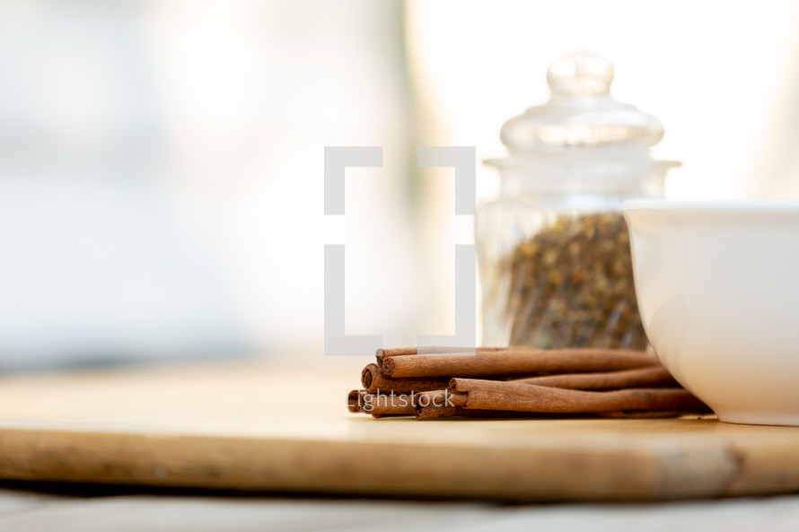 Cinnamon sticks with glass dishes on wooden cutting board