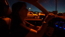 A woman driving in a parking lot at night
