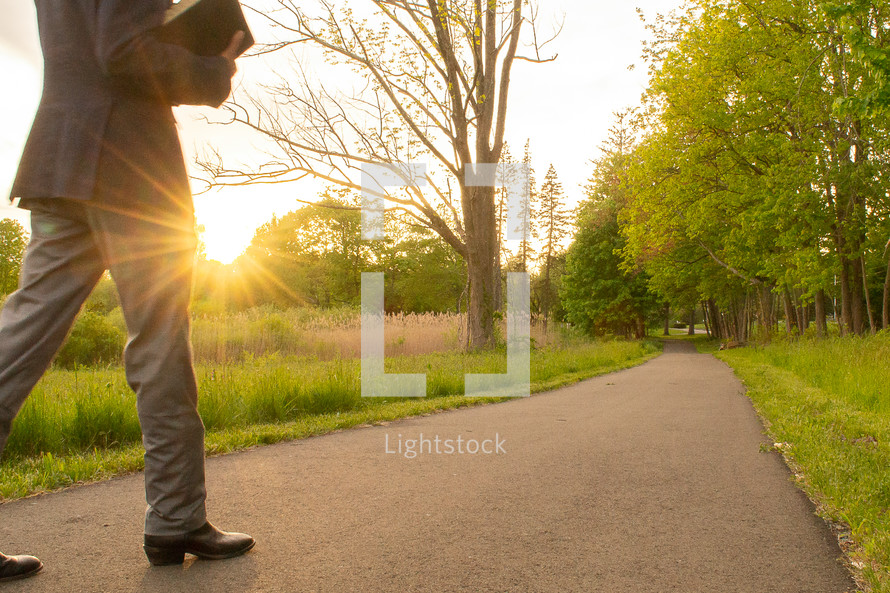 man carrying a Bible walking on a glowing path 