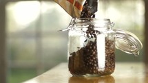 pouring coffee beans into a jar 