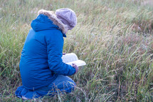 a woman reading a Bible outdoors in winter 