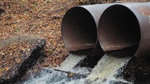 Environment protection concept. Industrial pipe discharging dirty waste. Runoff of excess water from the reservoir through metal pipes. Toxic waste in drain pipes.