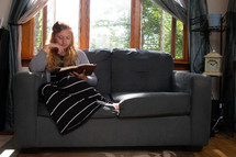 a woman reading a Bible on a couch 