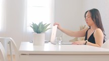 Female business owner responding to emails on laptop in stylish living room environment