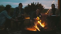 friends roasting marshmallows around a fire 