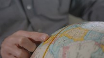 man looking at a globe 