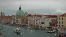 Overview of Venice's Grand Canal featuring the prominent San Simeone Piccolo church with its green dome and surrounding historic buildings