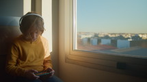 Boy sitting near a window playing games
