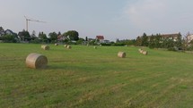 Aerial footage showing a quiet village with round hay bales in the foreground