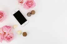 chocolates, cellphone, and pink roses on white 