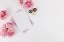 stationary, chocolates, and pink roses on a white background 