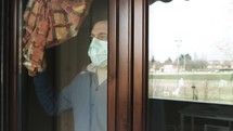 a man in a face mask looking out a window 