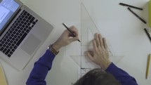 architect draws a building plan, measures the dimensions of the blueprint with a ruler 

