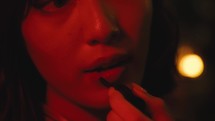 Girl wearing lipstick in old bar with red light