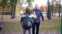 grandfather pushing his granddaughter on a swing 