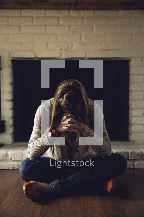 a pregnant woman sitting on the floor praying 
