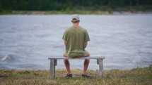 Person Sitting On A Bench By A River