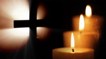 Cross and three candles in the dark.