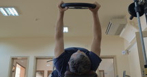 Low angle shot of a man exercising with weight plate.