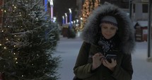 Woman using mobile walking in the street with Christmas decorations