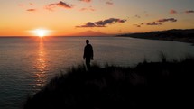 Silhouette of man on the top of mountain near the ocean