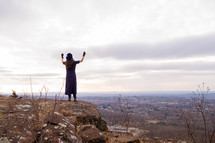 a woman standing on a mountaintop with raised hands 