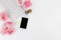 keyboard, chocolates, cellphone, and pink roses on a white desk 
