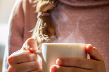 a woman holding a steaming coffee mug