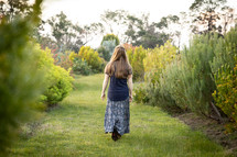 a girl walking on a grassy path 