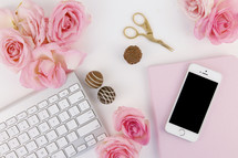 scissors, chocolates, pink roses, cellphone, and keyboard on a white desk 