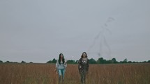 women walking in a field carrying sparklers 