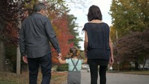 grandmother, grandfather, and granddaughter walking holding hands 