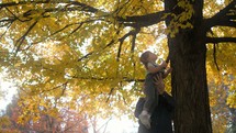 grandfather holding up his granddaughter to see falling autumn leaves 