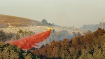 Fire fighter plane drops fire retardant on a forest fire in the hills