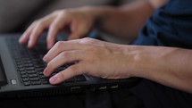 Close-up of hands of unrecognizable man typing on laptop keyboard while working at home office. Concept of working at home. Tracking shot in slow
