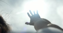 Bright light shines on hand of man raising his hand worshipping. Young man in worship, prayer and faith.