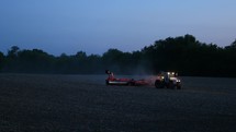 A farm tractor on the fields at dusk